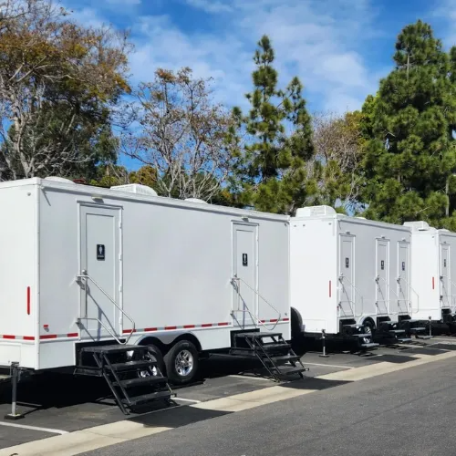 A row of Rocket Restrooms trailers lined up for a large outdoor event